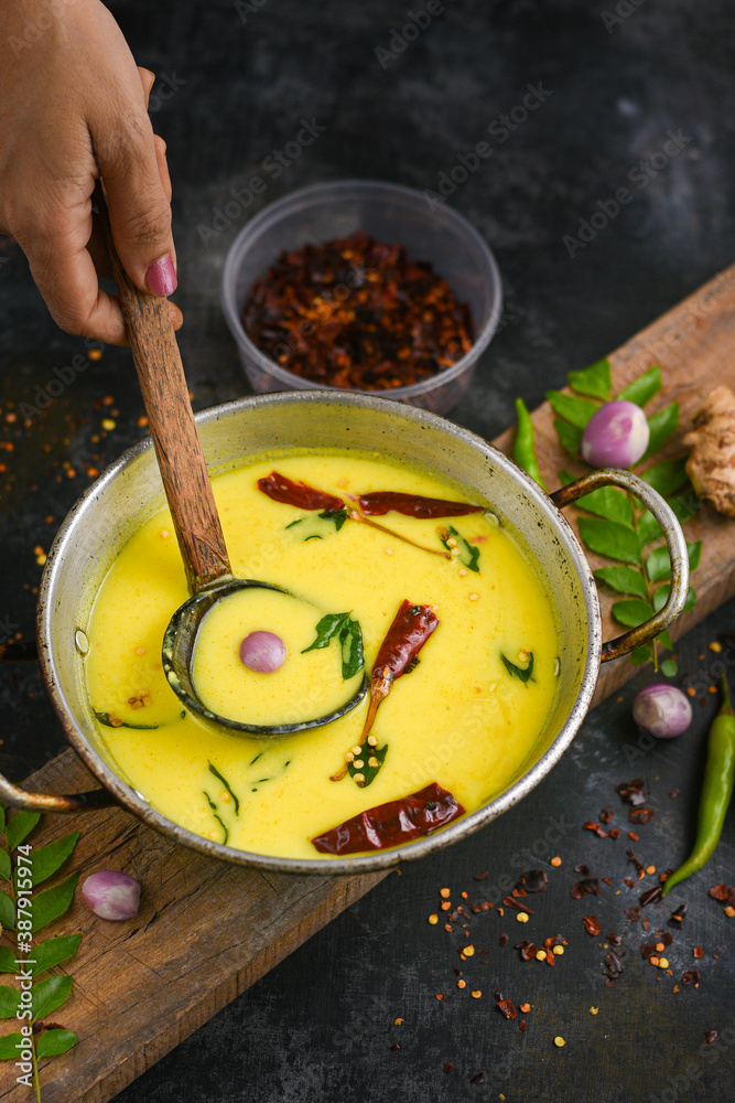 Woman hand make yellow spiced buttermilk curry Bowl homemade sour cream