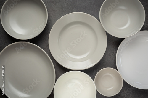 white round empty plates and bowls on dark background