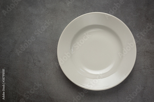 a white round empty plate on dark background