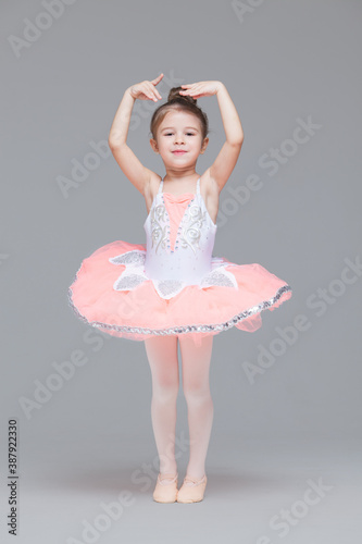 Cute adorable ballerina little girl in pink tutu dance practices ballet dancing