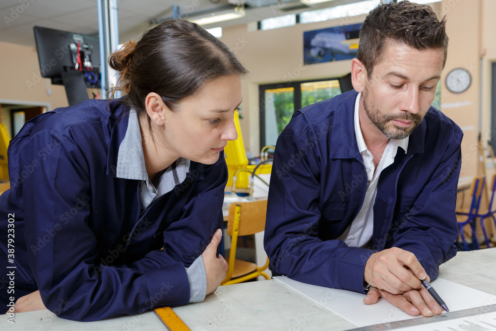 Fototapeta premium manual workers leaning over bench discussing paperwork