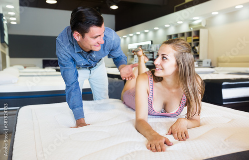 Positive man and woman choosing mattress in furniture store