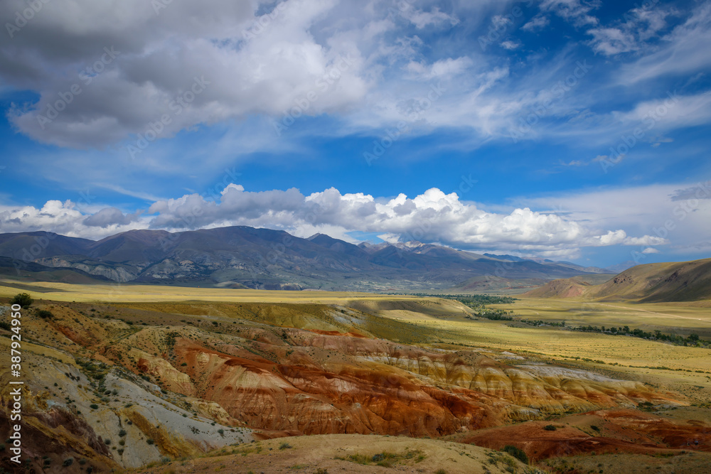Fantastic deserted mountain landscape on sunny day. Colorful rocks under blue sky with white clouds. Wild and lost corners of the planet, Martian landscape in the Altai.