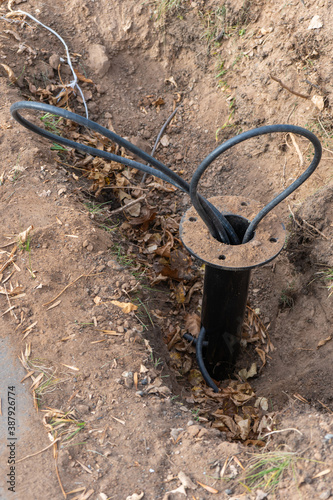 Protruding wires from the ground, the base for a new street lamp. Installation of street lighting
