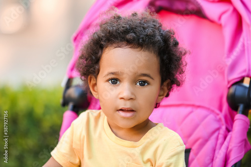 Cute African-American baby in stroller outdoors