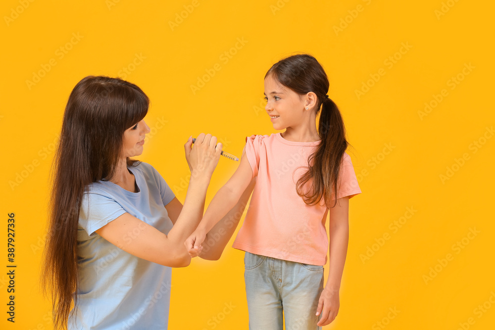 Mother giving her diabetic daughter insulin injection on color background Mother giving her diabetic daughter insulin injection on color background