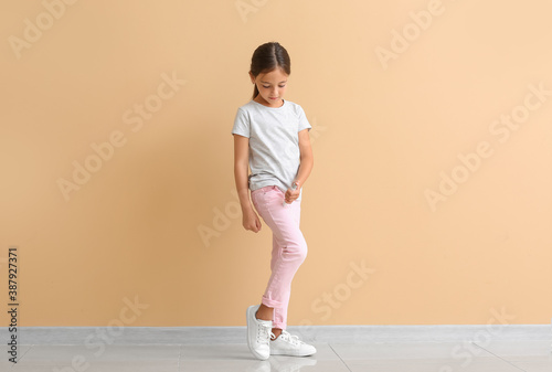 Little diabetic girl giving herself insulin injection near color wall