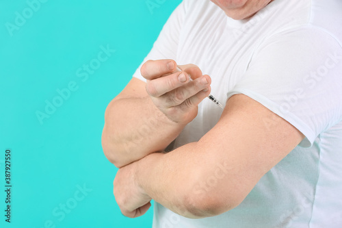Senior diabetic man giving himself insulin injection on color background