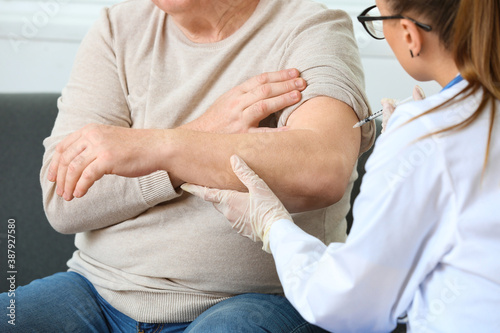 Doctor giving senior diabetic man insulin injection at home