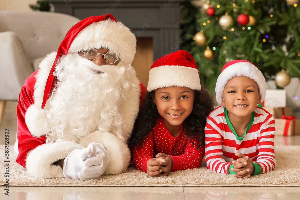 African-American Santa Claus with cute children at home on Christmas eve African-American Santa Claus with cute children at home on Christmas eve