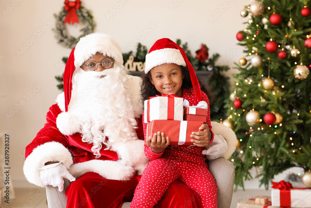 African-American Santa Claus and cute girl with gifts at home on Christmas eve