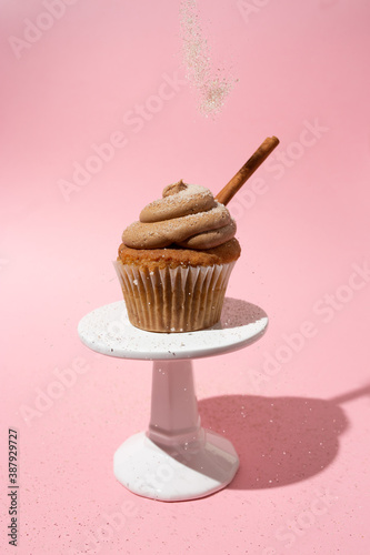 Cinnamon cupcake with frosting and s cinnamon stick on a white pedestal
