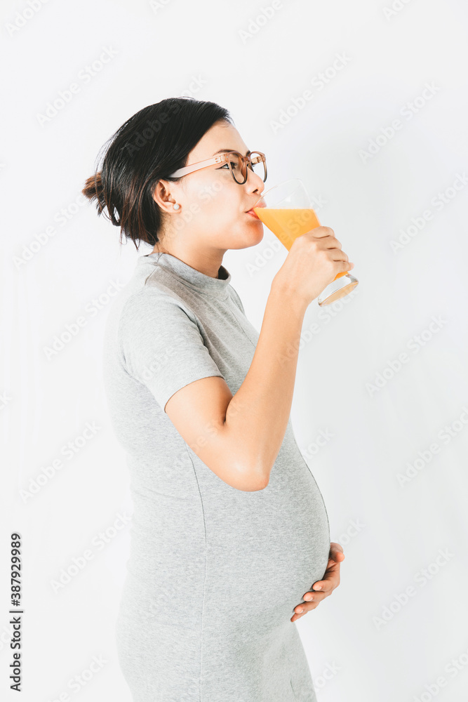 Asian pregnant woman standing drinking orange juice In a relaxed mood.