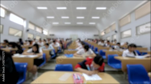 Blurred Time Lapse of Asian students taking an exam in classroom