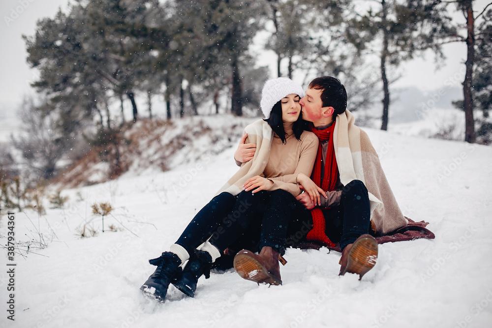 Fototapeta premium Young couple in a winter park. Man with a red sharf. Lady in a red jacket