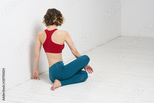 woman doing yoga full length indoors blue leggings red tank top