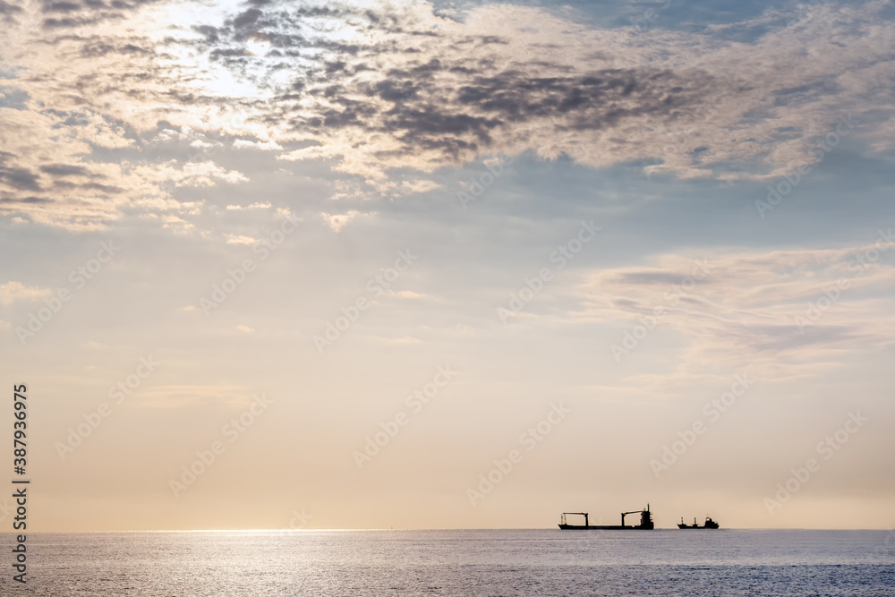 Distant and minimal view of the merchant ships. A bulk carrier, bulker is a merchant ship specially designed to transport unpackaged bulk cargo, such as grains, coal, ore, steel coils. Distant and minimal view of the merchant ships. A bulk carrier, bulker is a merchant ship specially designed to transport unpackaged bulk cargo, such as grains, coal, ore, steel coils.