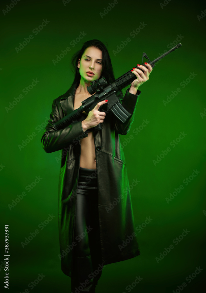 a woman in a black leather raincoat with an American automatic rifle on a green background