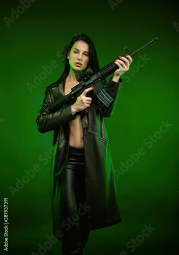 a woman in a black leather raincoat with an American automatic rifle on a green background