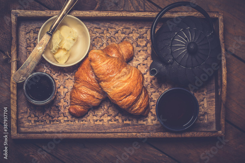 French croissant. Freshly baked croissants with jam on wooden background. Tasty croissants with copy space