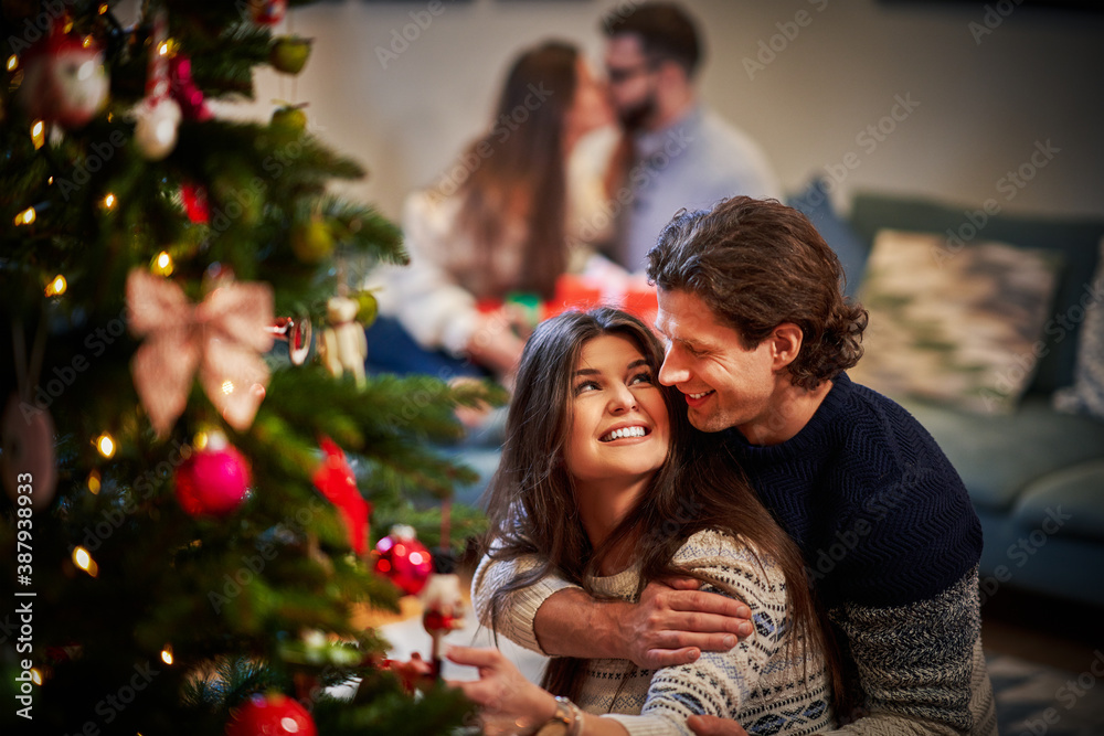 Adult couples having fun over Christmas tree