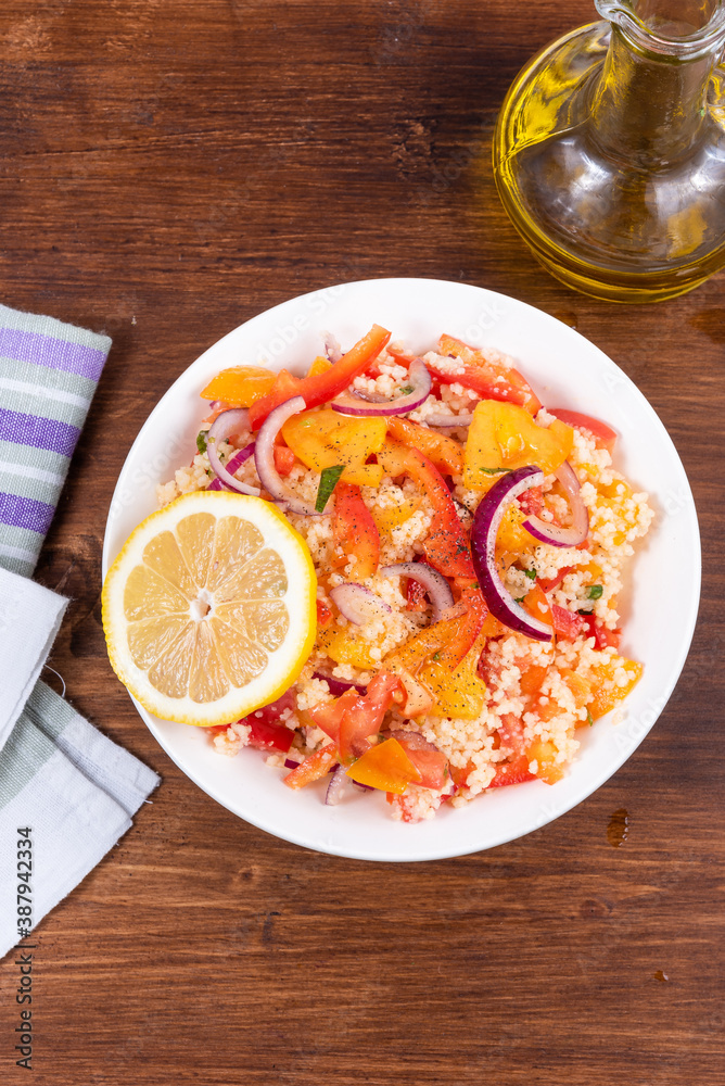 Traditional Mediterranean salad of couscous, tomato, pepper and onion in a plate on a wooden table, close-up, top view - Moroccan and Algerian cuisine Traditional Mediterranean salad of couscous, tomato, pepper and onion in a plate on a wooden table, close-up, top view - Moroccan and Algerian cuisine