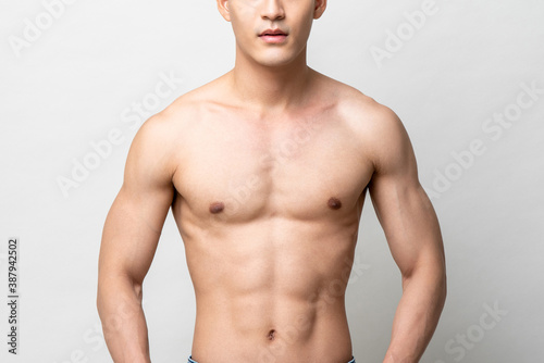 Healhty muscular upper body of a shirtless man isolated on light gray studio background