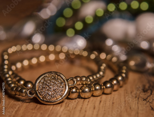 Pearl necklace on a wooden background. Golden colored pearl bracelet with crystals in the front, on a colored background with bokeh