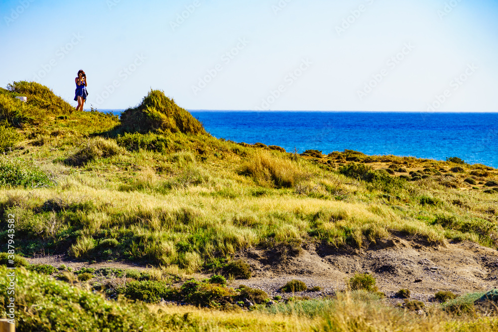 Woman walk on seashore, take photo with camera