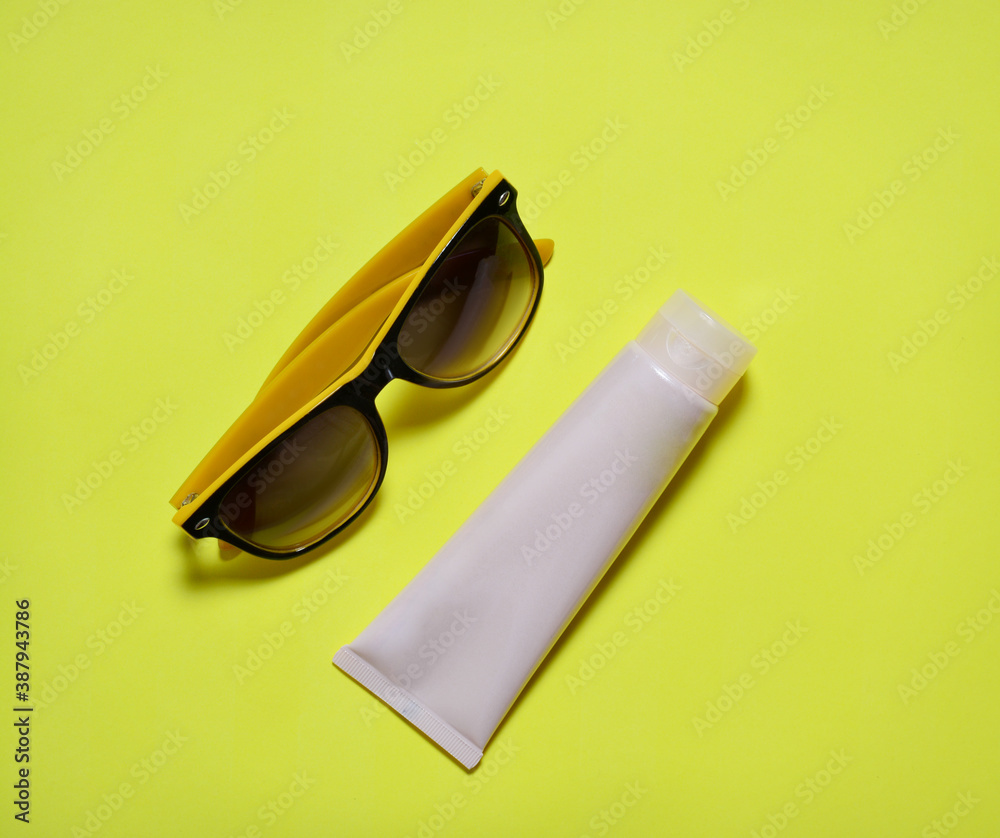 sun cream and sun glasses on yellow background. the concept of a vacation flight to rest, vacation in warm regions. sun cream and sun glasses on yellow background. the concept of a vacation flight to rest, vacation in warm regions.