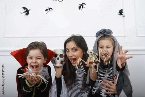 Happy family with children in costumes of witch and vampire in a house in holiday Halloween