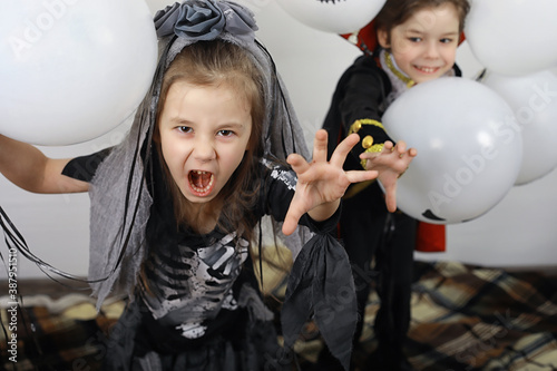 Happy family with children in costumes of witch and vampire in a house in holiday Halloween