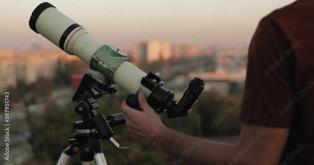 Amateur astronomer looking at the stars with a telescope with blurred city background. Amateur astronomer looking at the stars with a telescope with blurred city background.