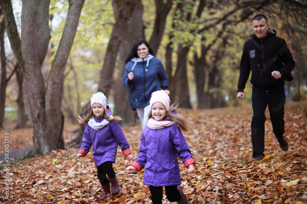 Young family on a walk in the autumn park on a sunny day. Happiness to be together.