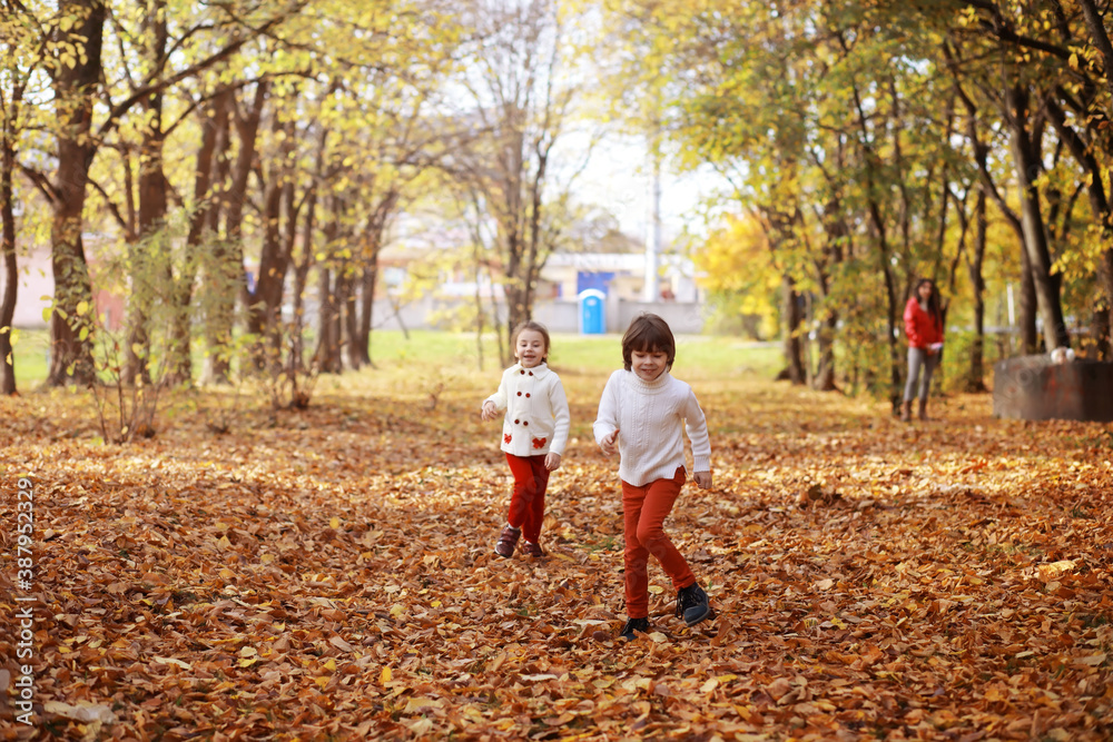 Young family on a walk in the autumn park on a sunny day. Happiness to be together.