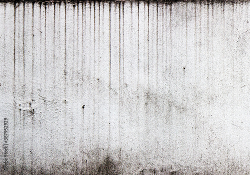 Vertical streaks of dirt on a white textured wall