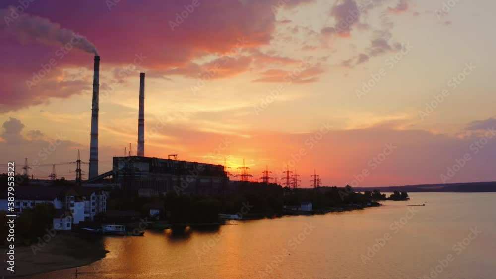 Harmful factory against pink sky at sunset. Smoke from the industrial chimney pollute the environment. Chemical plant near the evening river. Harmful factory against pink sky at sunset. Smoke from the industrial chimney pollute the environment. Chemical plant near the evening river.