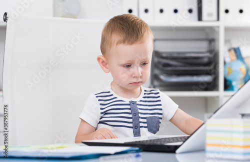 Child is playing on laptop in the office.