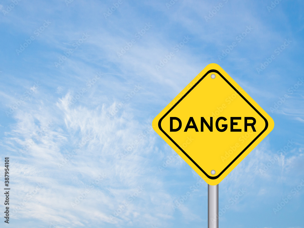 Yellow transportation sign with word danger on blue sky background Yellow transportation sign with word danger on blue sky background