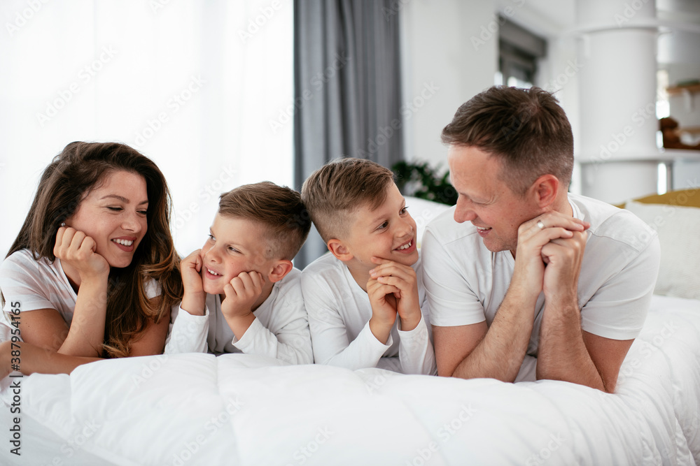 Young family enjoying in bed. Happy parents with sons relaxing in bed Young family enjoying in bed. Happy parents with sons relaxing in bed