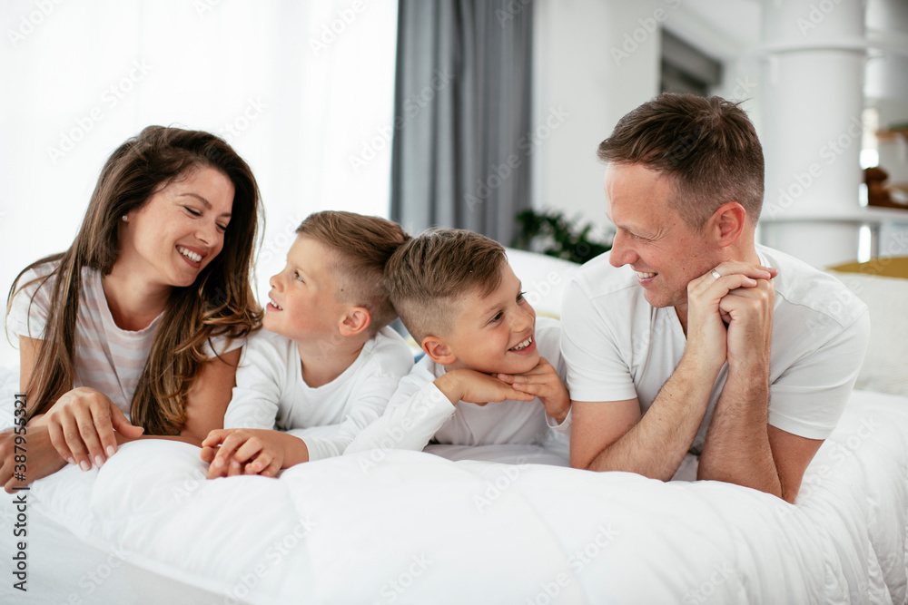 Young family enjoying in bed. Happy parents with sons relaxing in bed Young family enjoying in bed. Happy parents with sons relaxing in bed