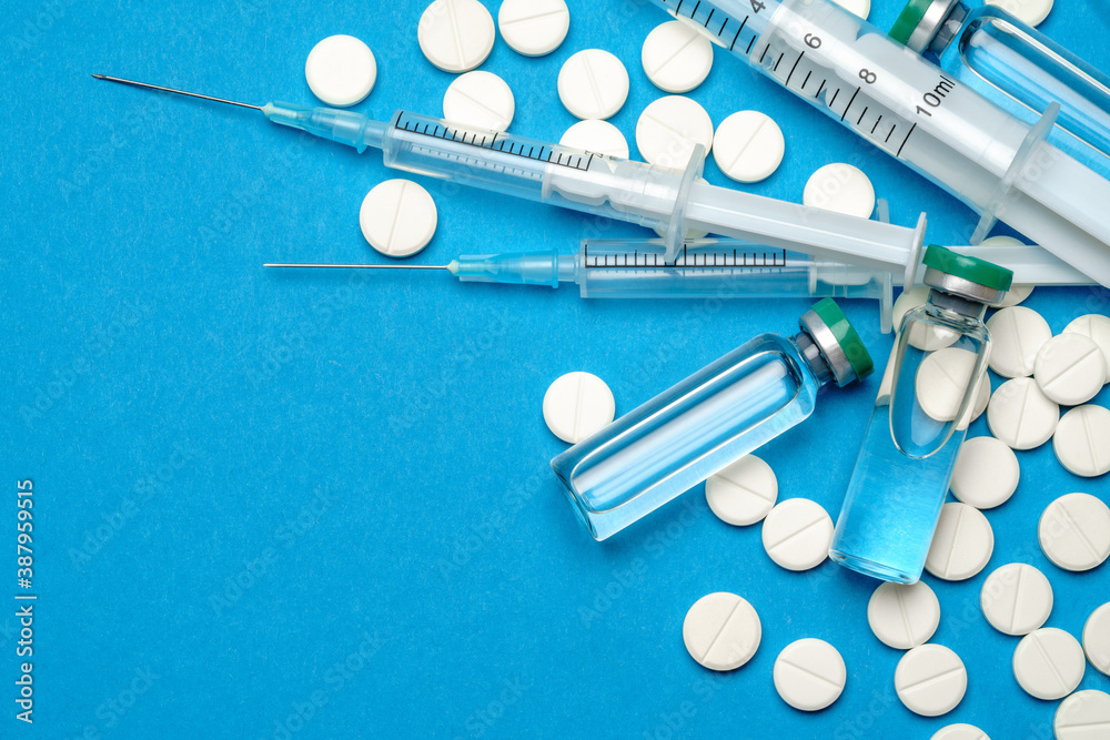 Top view of Pills, Syringe And Ampoule With Vaccination On blue background with copy space Top view of Pills, Syringe And Ampoule With Vaccination On blue background with copy space