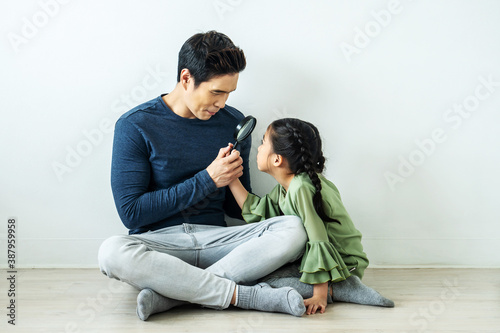 Happy father playing magnifying glass with a daughter in home