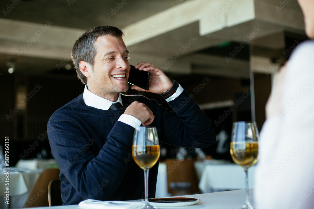 Handsome businessman dressed in the suit drinking wine. Businessman talking to the phone.