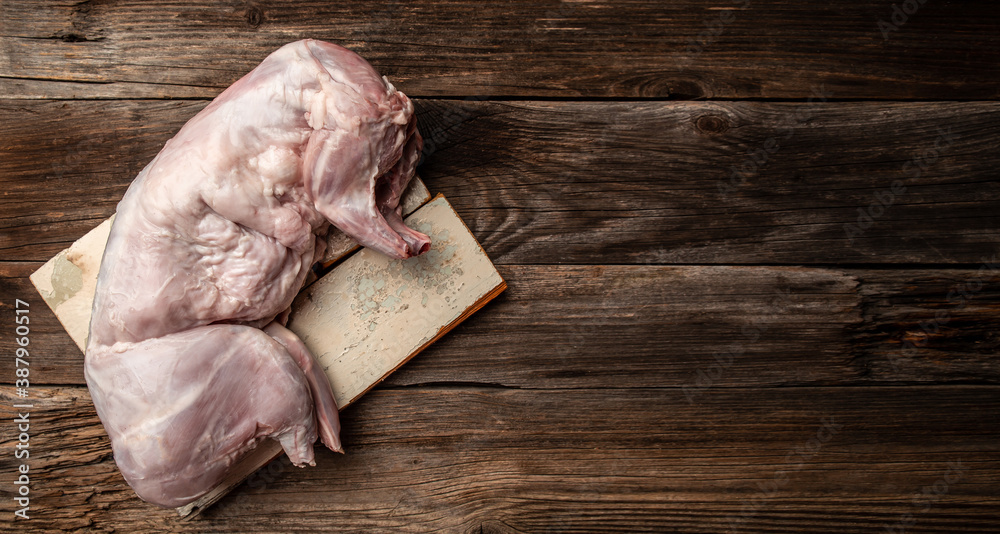Raw rabbit meat on a wooden table. meat carcass of a fresh rabbit. Whole rabbit ready to cook. Long banner format, top view