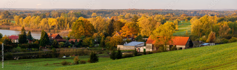 Autumn countryside landscape - green fields, trees in autumn clothes and a lake