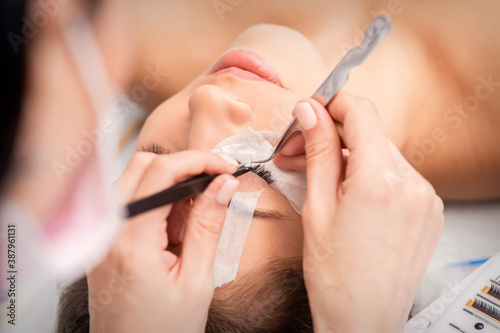 Young caucasian woman receiving eyelash extensions procedure in beauty salon