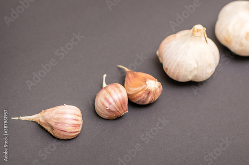 Still life of two garlic heads and garlic cloves grouped on dark background