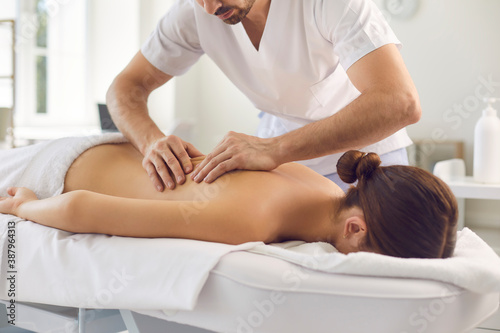 Woman patient getting back massage procedure from professional chiropractor