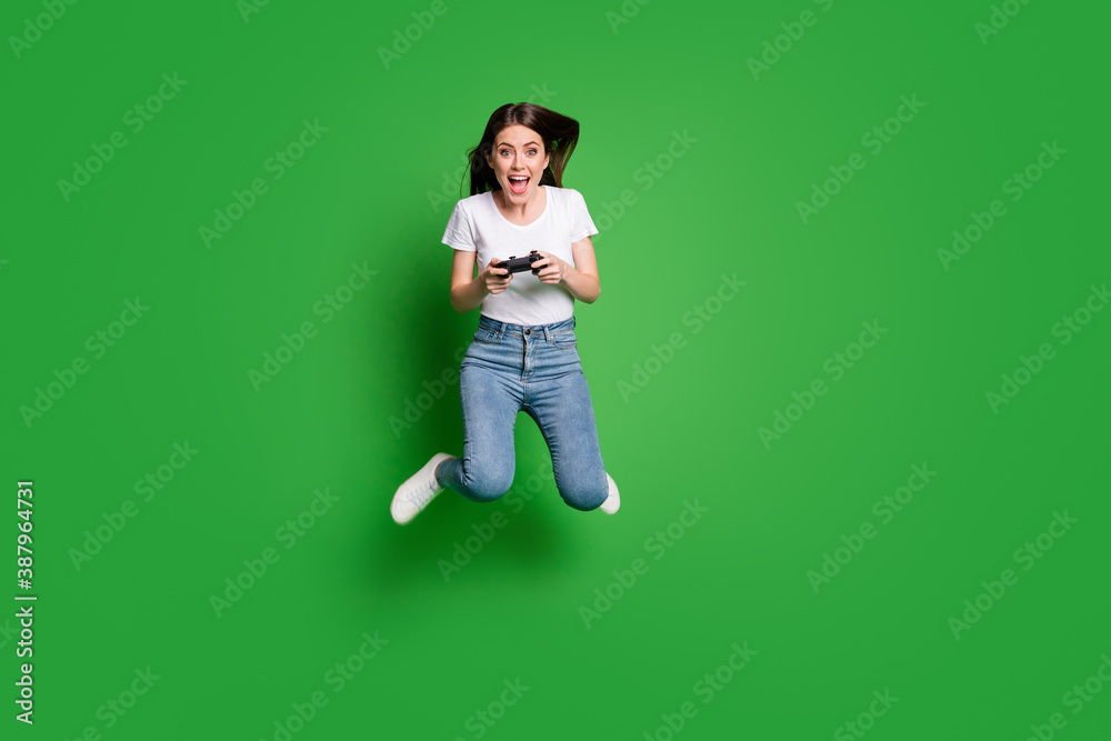 Full length photo of crazy girl jump play video game isolated over bright green color background Full length photo of crazy girl jump play video game isolated over bright green color background
